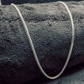 Gray textured rug with a white rope border on a dark gray background