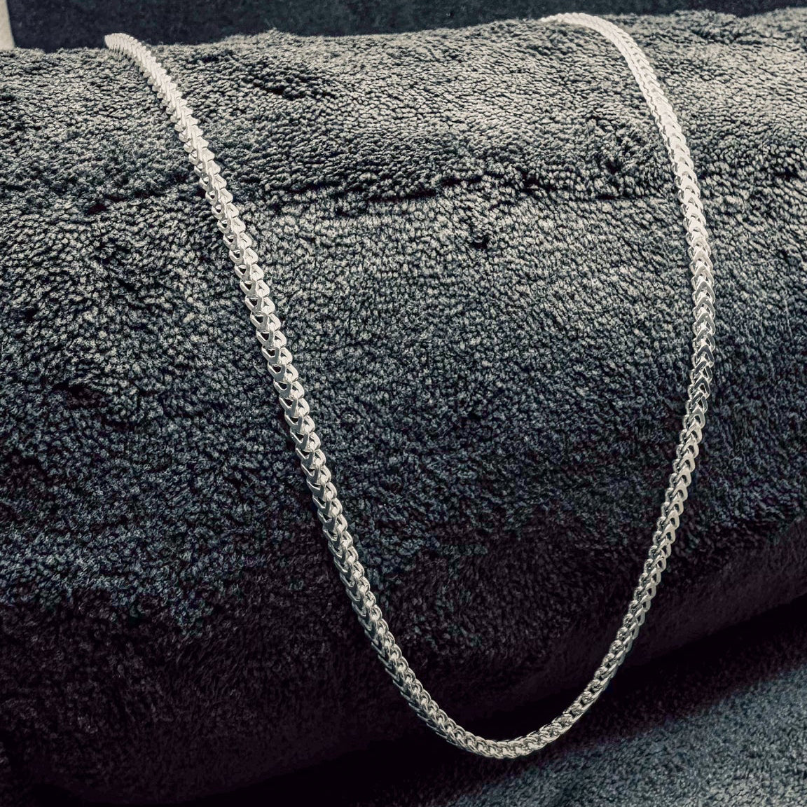 Gray textured rug with a white rope border on a dark gray background