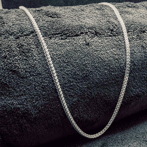 Gray textured rug with a white rope border on a dark gray background