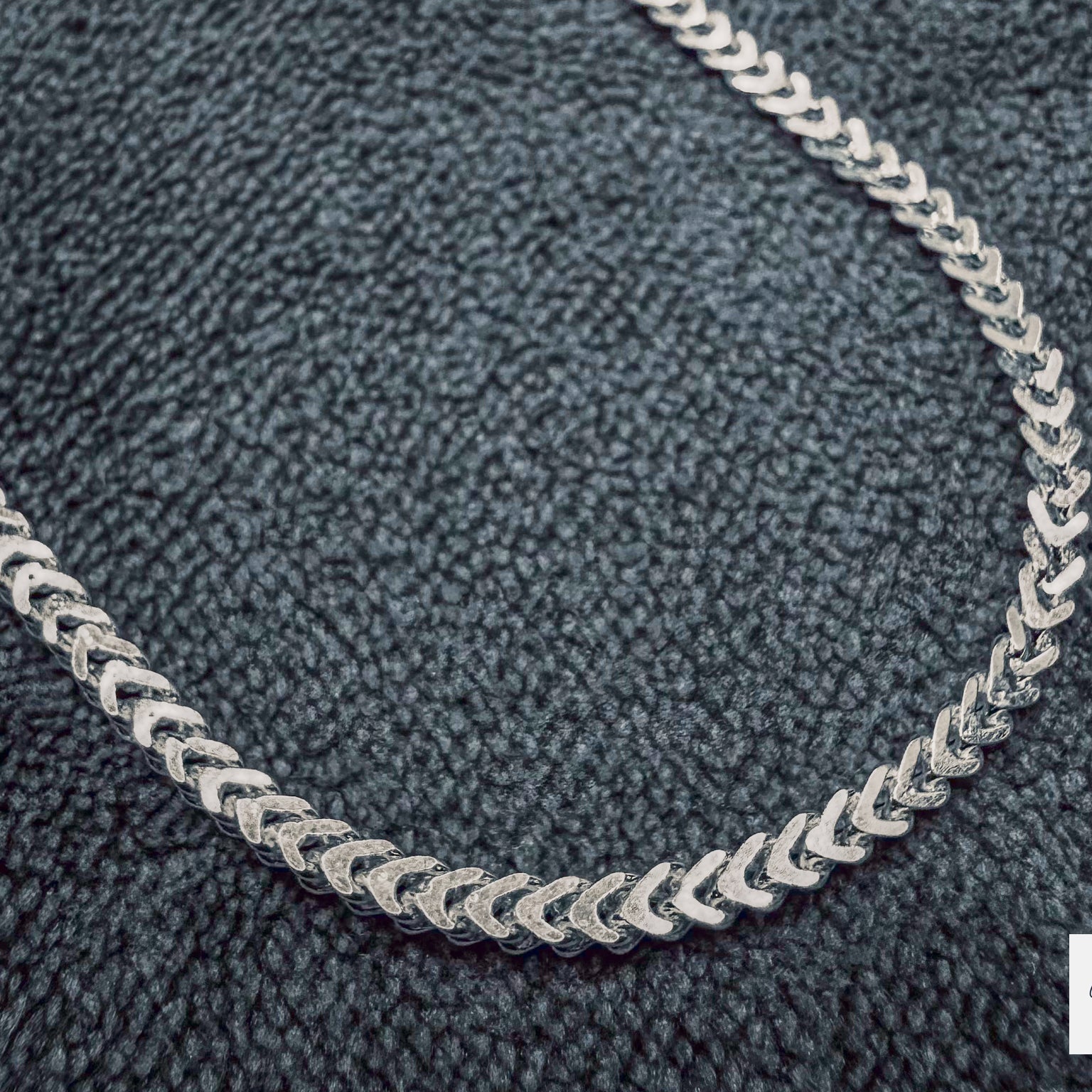 Silver chain necklace on a textured gray surface