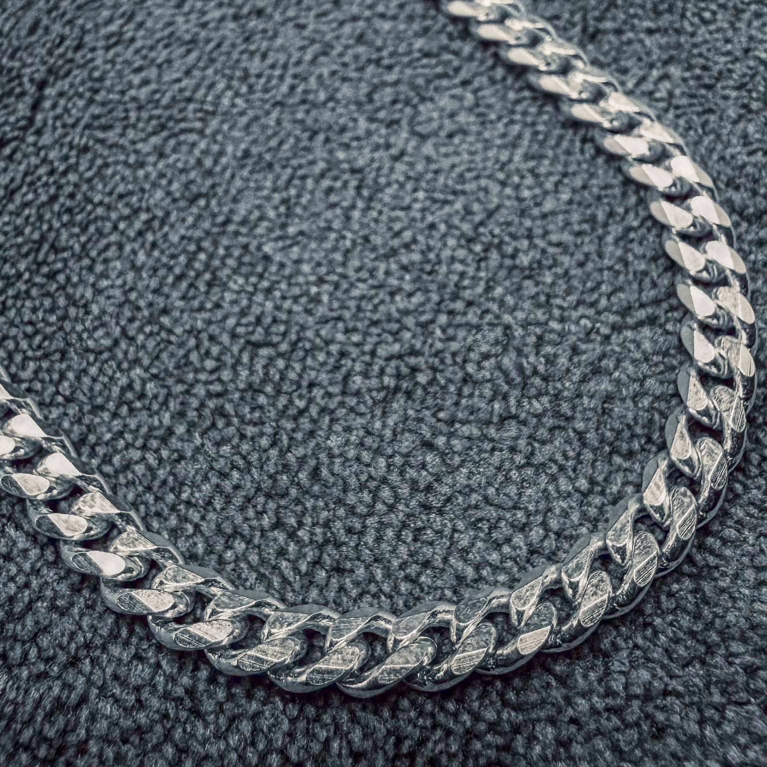 Silver chain necklace on a textured gray surface