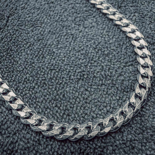 Silver chain necklace on a textured gray surface