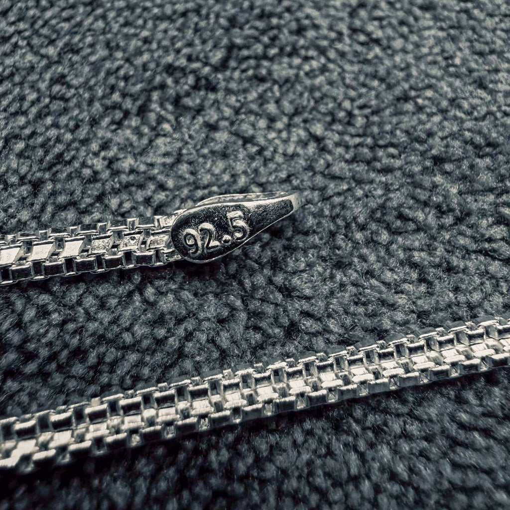 Silver chain with '925' stamp on a textured gray surface