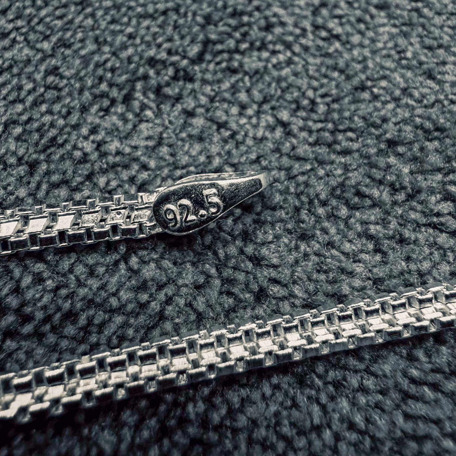 Silver chain with '925' stamp on a textured gray surface