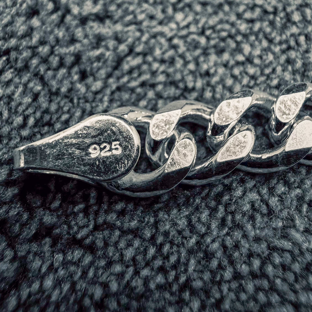 Close-up of a silver chain with '925' stamp on a textured surface