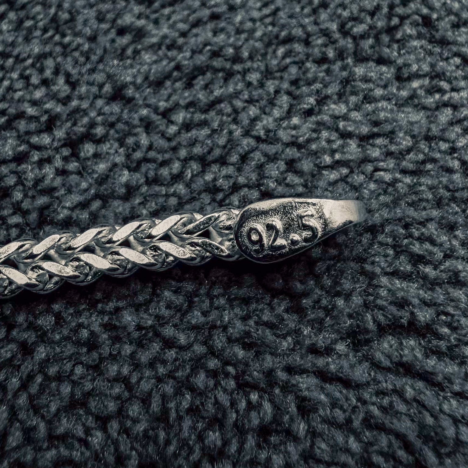 Close-up of a silver bracelet on a textured dark surface