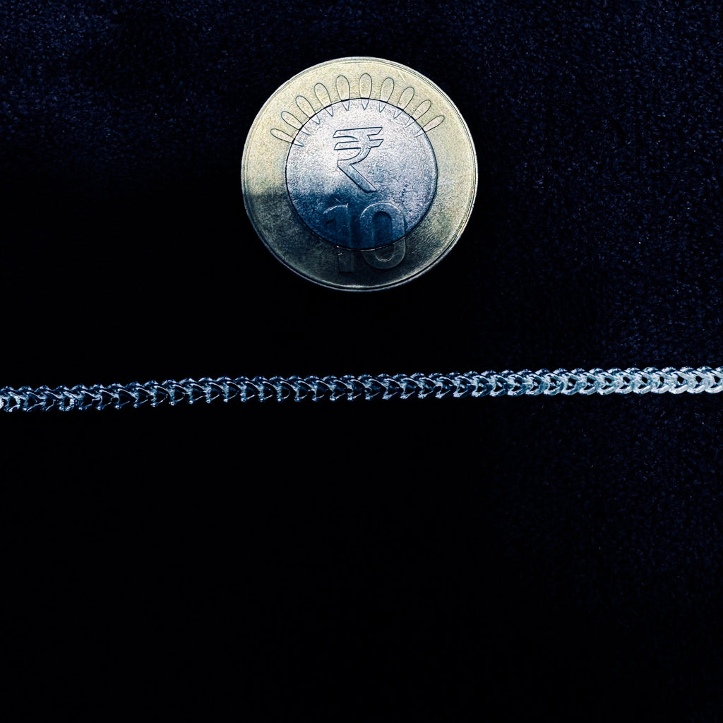 Silver chain with a 10 centavo coin on a black background