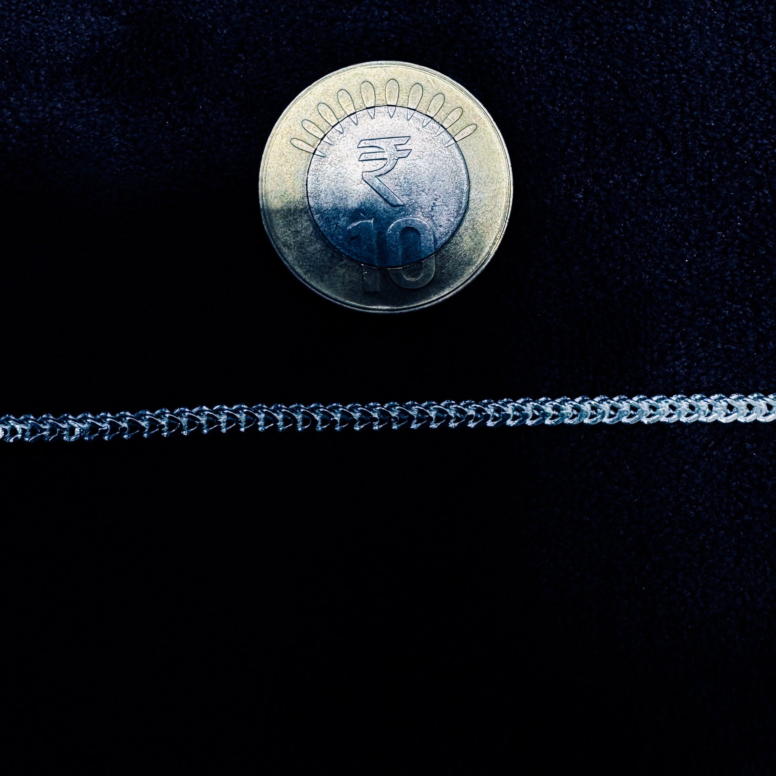 Silver chain with a 10 centavo coin on a black background