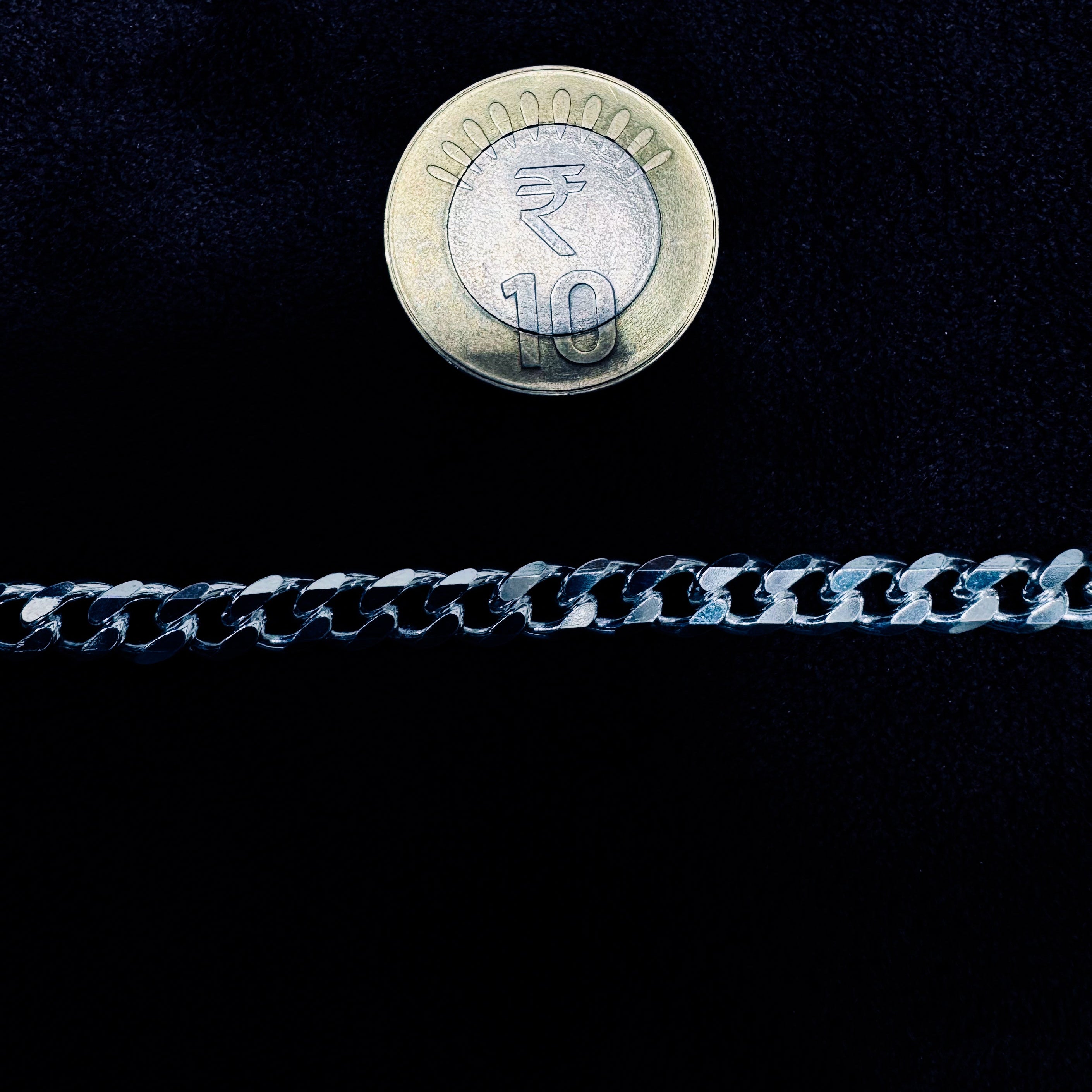 Ten rupee coin on a chain against a black background